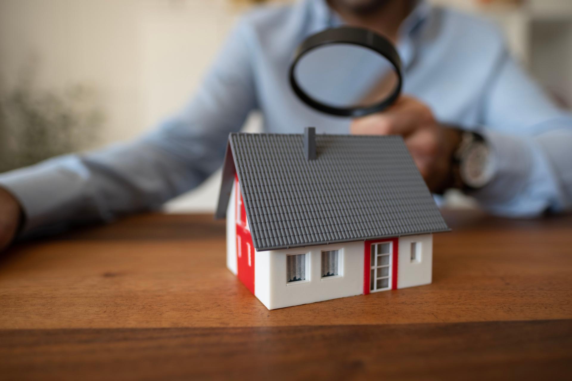 Real estate agent holding small house model. Mortgage and real estate investment concept.